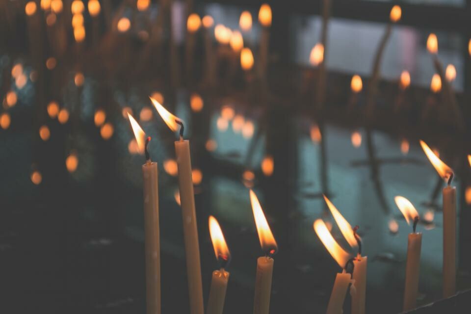 A dimly lit room filled with many glowing candles, casting soft light and shadows around the space.