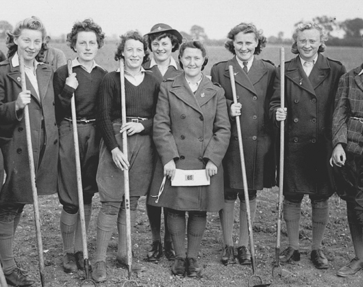 A group of Land Girls in uniform, holding shovels in a field at Hale Nursery, circa 1945.